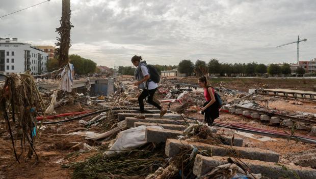 Dos chicas cruzan por las vías de la Línea 1 del Metro de Valencia tras el paso de la DANA