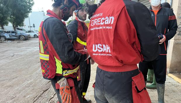 Miembros del Grupo Internacional de Rescate (GIRECAN) hablando con algunos vecinos antes de acceder al interior de un garaje