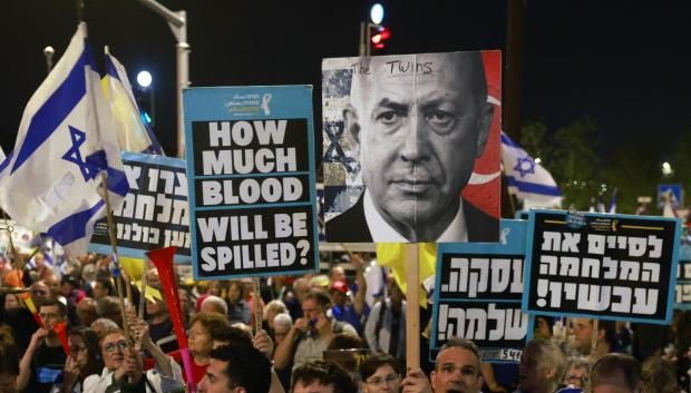 Un hombre sostiene una pancarta con retratos a medias del primer ministro israelí, Benjamin Netanyahu (izq.), y del presidente turco, Recep Tayyip Erdogan (der.), durante una protesta de manifestantes antigubernamentales israelíes que exigen el fin de la guerra en Gaza y el regreso de todos los rehenes retenidos por Hamás,