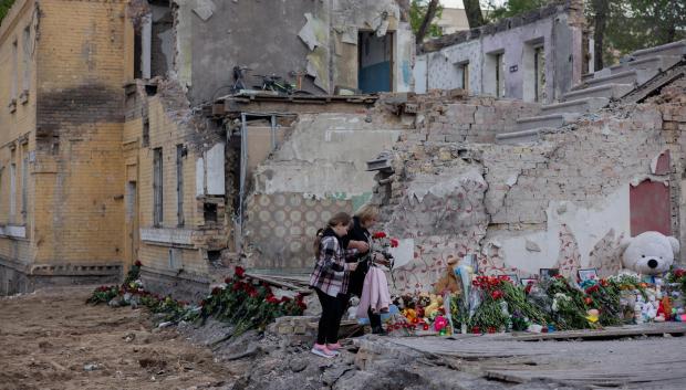 Residentes locales depositan flores en el lugar de un edificio residencial destruido tras un ataque con misiles rusos en Kiev