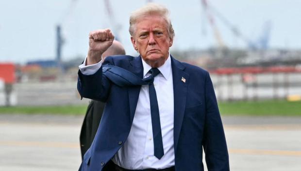 El presidente de Estados Unidos, Donald Trump, levanta el puño al descender del avión de la Fuerza Aérea
