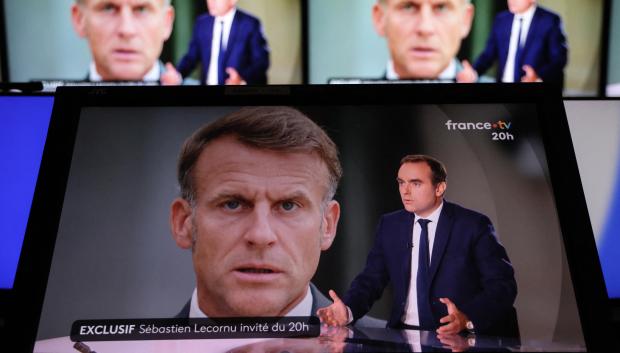 El primer ministro francés, Sébastien Lecornu, dando una entrevista con el rostro de Macron detrás