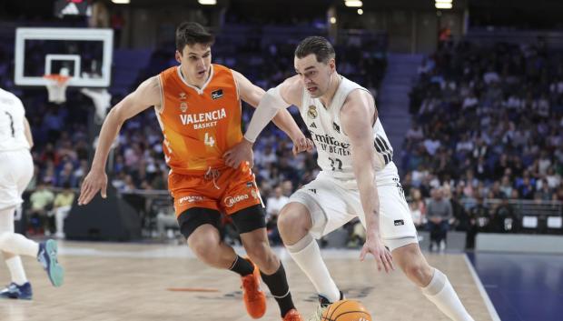 El alero del Real Madrid Mario Hezonja (d) juega un balón ante el ala-pívot Jaime Pradilla, del Valencia
