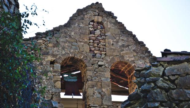 Campanario de la iglesia de Armejún visto a través de un muro de piedra seca semi-arruinado