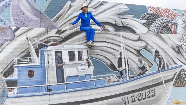 La muralista Lula Goce posa junto a su mural durante una entrevista