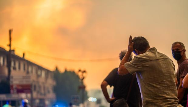Varias personas observan el fuego durante las labores de extinción del incendio forestal en La Adrada.