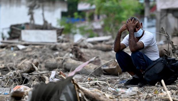 Un hombre se sienta junto a los escombros mientras recupera sus pertenencias tras unas inundaciones repentinas en Devighat, en el distrito nepalí de Nuwakot