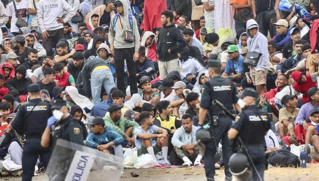 Un grupo de policías custodiando a un grupo de inmigrantes ilegales en Ceuta