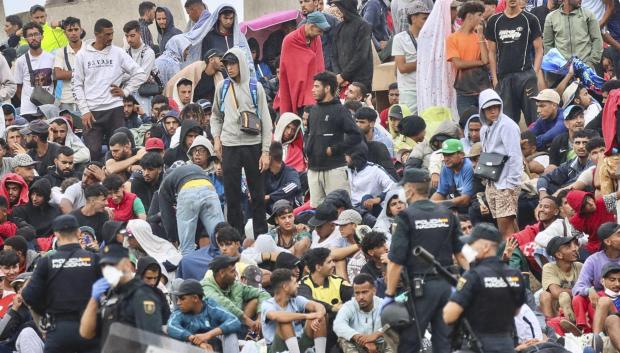 Un grupo de policías custodiando a un grupo de inmigrantes ilegales en Ceuta