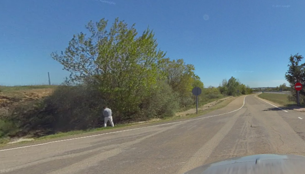Un conductor orinando en un área de descanso, cerca las mesas para los usuarios
