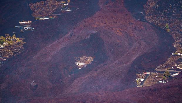 La lava sigue su curso hacia el mar. En la imagen esquiva una vivienda situada en un pequeño alto
