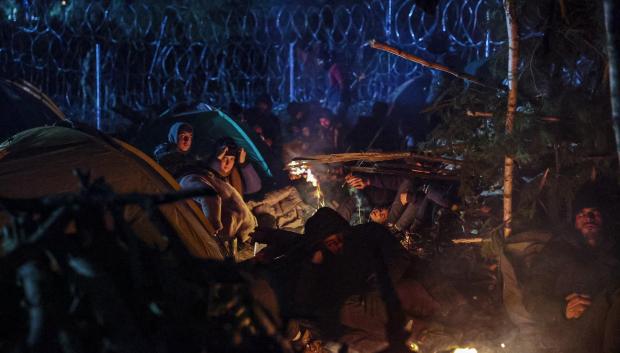 Un grupo de inmigrantes se calienta en una hoguera en un campamento en la región de Grodno