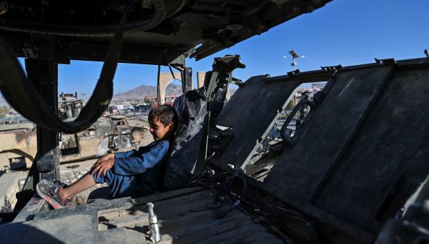 Un niño descansa en el interior de un vehículo militar estadounidense calcinado