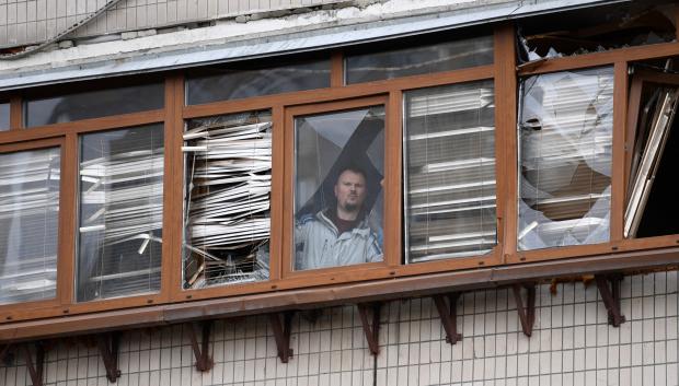 Un hombre mira por la ventana de un edificio afectado por los bombardeos en Kiev
