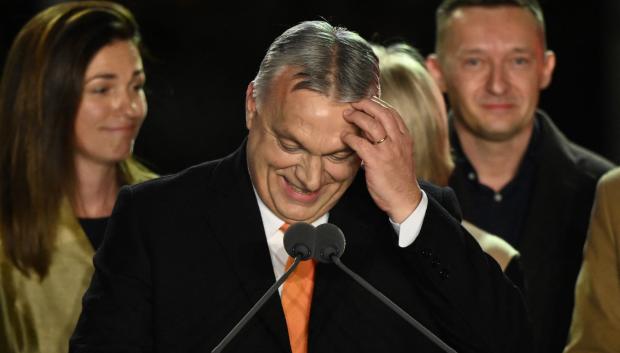 Hungarian Prime Minister Viktor Orban delivers a speech on stage next to members of the Fidesz party at their election base, 'Balna' building on the bank of the Danube River of Budapest, on April 3, 2022. - Nationalist Hungarian Prime Minister Viktor Orban claimed a "great victory" in general election, as partial results gave his Fidesz party the lead. (Photo by Attila KISBENEDEK / AFP)
