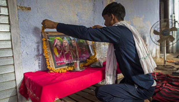 A man places a garland over the portrait of the three married sisters, who were all found dead along with another child in a well in Dudu village on May 28, at the family home in Chhapya village of India's Rajasthan state on May 31, 2022. - Before the three sisters and their children were found dead in a well, they left a message blaming the family they had married into. Kalu, Kamlesh and Mamta Meena were victims of a dispute over dowries, the often hefty sums Indian parents pay to marry off their daughters. (Photo by Xavier Galiana / AFP)