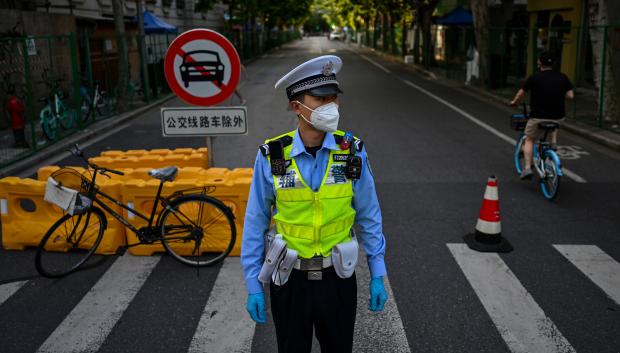 Un policía vigila una calle al lado de un área residencial bajo bloqueo de Covid-19 en el distrito Xuhui de Shanghai