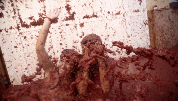 Dos personas cubiertas de tomate durante la fiesta