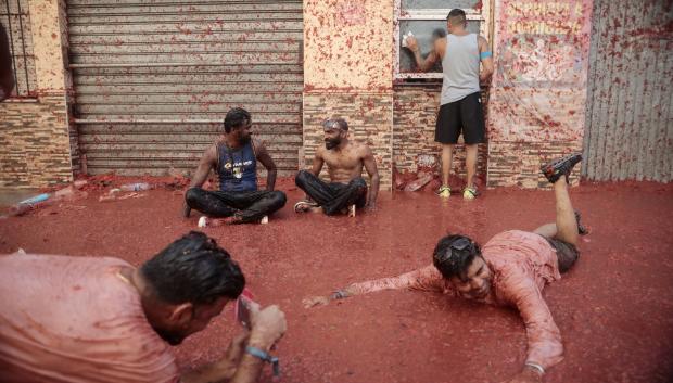 Varias personas se bañan por los ríos de tomate de las calles de Buñol
