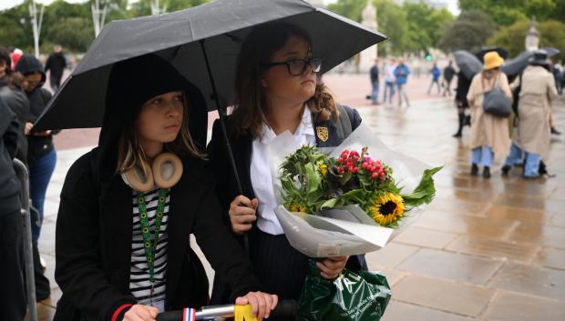 Mujeres esperan, con flores, frente a Buckingham Palace