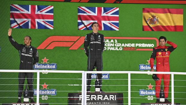 (L to R) Mercedes' British driver Lewis Hamilton, Mercedes' British driver George Russell, and Ferrari's Spanish driver Carlos Sainz Jr celebrate their second, first and third place respectively in the podium of the Formula One Brazil Grand Prix, at the Autodromo Jose Carlos Pace racetrack, also known as Interlagos, in Sao Paulo, Brazil, on November 13, 2022. (Photo by NELSON ALMEIDA / AFP)