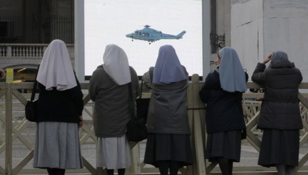 Nuns watch a giant screen showing  a helicopter with Pope Benedict XVI onboard in St. Peter's Square, at the Vatican,Thursday, Feb. 28, 2013.
