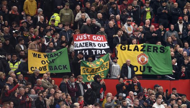 Los aficionados del Manchester United muestran la pancarta pidiendo la dimisión de la familia Glazer.