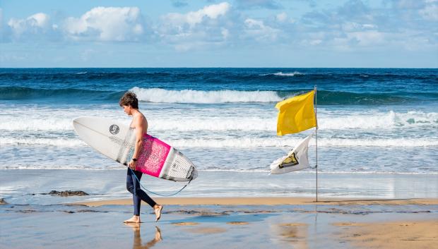 Un surfista pasea por la playa de las Canteras, en Las Palmas de Gran Canaria