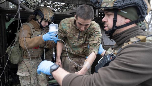 Medics from the Da Vinci Wolves Battalion evacuate a lightly wounded Ukrainian serviceman near the frontline near Bakhmut, Donetsk region, on April 1, 2023, amid the Russian invasion of Ukraine. - Churned-up roads have been turned into quagmires by melted snow, making the journey slow. The ambulance is coated in mud from wheels to roof. (Photo by Genya SAVILOV / AFP)