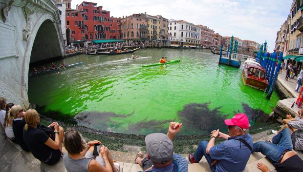 Turistas observan el agua verde del Gran Canal de Venecia