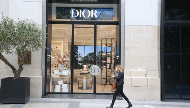 People wearing protective face masks strolling close from Dior store on the Champs Elysee avenue on May 11, 2020 in Paris, France.