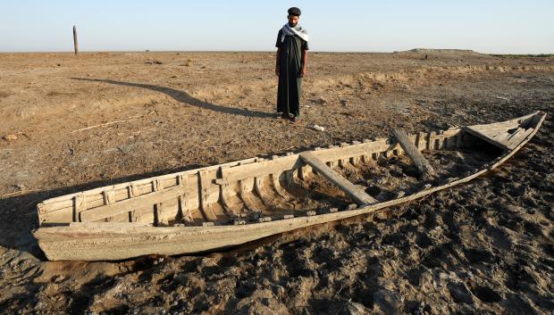 Un hombre iraquí mira un bote varado a lo largo de un banco seco