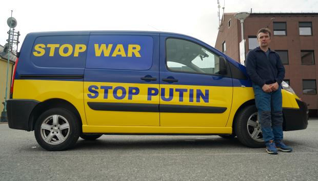 El manifestante ruso Anton Kalinin posa junto al automóvil que decoró con las letras "Stop War" y "Stop Putin"