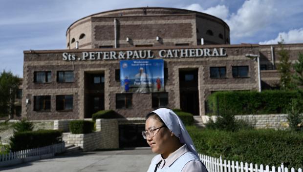 A nun walks past Sts. Peter and Paul Catholic Cathedral adorned with a poster of Pope Francis in Ulaanbaatar on August 31, 2023. Pope Francis is set to visit Mongolia and tour the Buddhist-majority nation's capital at the government's invitation this week, becoming the first pontiff to set foot there. (Photo by Pedro PARDO / AFP)