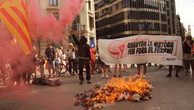 Jóvenes miembros de Arran, vinculado a la CUP, quema en la Diada una bandera de España y un muñeco con la cara de Abascal