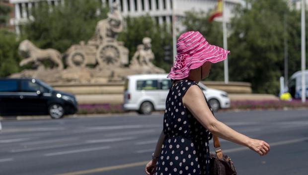 Una mujer pasea por una calle de Madrid con sombrero en pleno episodio de calor