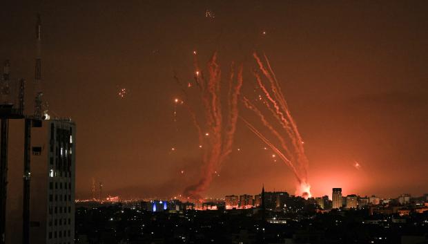 A salvo of rockets is fired by Palestinian militants from Gaza as an Israeli missile launched from the Iron Dome defence missile system attempts to intercept the rockets, fired from the Gaza Strip, over the city of Netivot in southern Israel on October 8, 2023. - Israel, reeling from the deadliest attack on its territory in half a century, formally declared war on Hamas Sunday as the conflict's death toll surged close to 1,000 after the Palestinian militant group launched a massive surprise assault from Gaza. (Photo by MAHMUD HAMS / AFP)