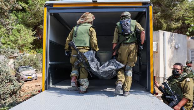 Israeli soldiers remove the body of a compatriot, killed during an attack by the Palestinian militants, in Kfar Aza, south of Israel bordering Gaza Strip, on October 10, 2023. Israel pounded Hamas targets in Gaza on October 10 and said the bodies of 1,500 Islamist militants were found in southern towns recaptured by the army in gruelling battles near the Palestinian enclave. (Photo by JACK GUEZ / AFP)