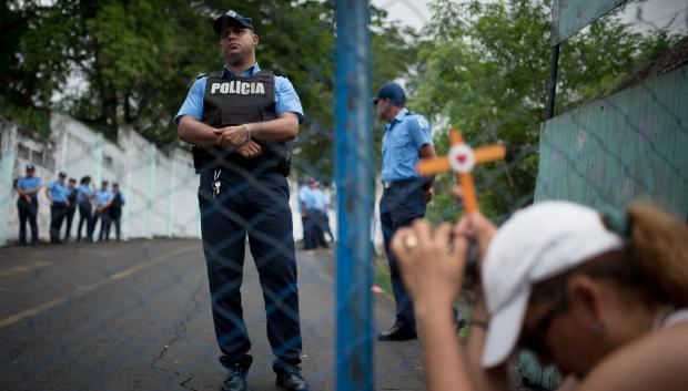 Una mujer sostiene una cruz frente a la cárcel de El Chipote