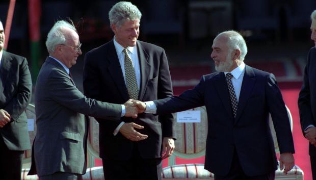 Bill Clinton observa cómo se dan la mano el rey Hussein de Jordania y el primer ministro israelí Isaac Rabin