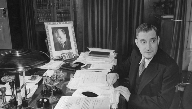 António de Oliveira Salazar sentado en su escritorio con un retrato autografiado de Mussolini