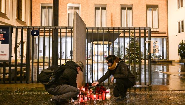 Varias personas ponen velas delante de la universidad de Praga en memoria de las víctimas del tiroteo