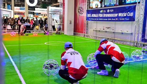 Los competidores colocan su dron en posición para un partido de fútbol con drones con dos equipos de cinco jugadores que compiten con drones envueltos en carcasas protectoras de alambre para que parezcan pelotas en el aire y los puntos se obtienen al maniobrar el dron a través del aro del equipo contrario, que se ilumina cuando se marca un gol.