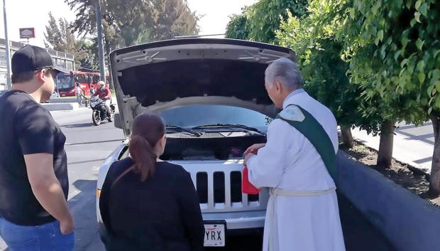 El sacerdote rocía con agua bendita el exterior, el interior e incluso el motor