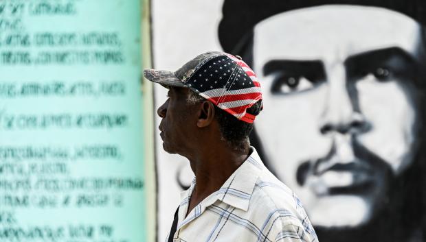 Un hombre junto a una pared pintada con un retrato del líder revolucionario Che Guevara