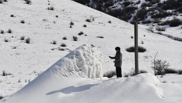 Un hombre en el glaciar artificial en un desfiladero de montaña cerca del pueblo de Syn-Tash