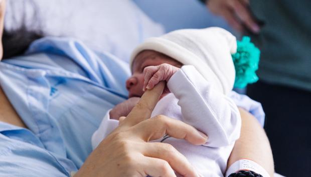 Un bebé recién nacido agarra la mano de su madre