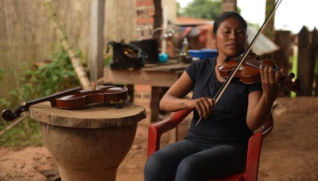 Una joven toca el violín en la Amazonía