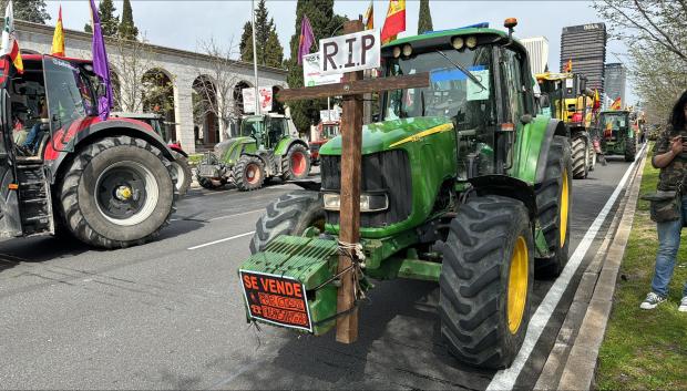 Un tractor porta una cruz y un cartel de "se vende" como símbolo de protesta