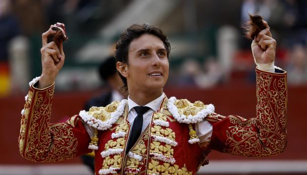 Roca Rey presenta al público las dos orejas cortadas a su primer astado durante la corrida de toros de la Feria de Fallas, con reses de Jandilla y Vegahermosa, y en la que ha compartido cartel con Talavante y José María Manzanares. EFE/Biel Aliño